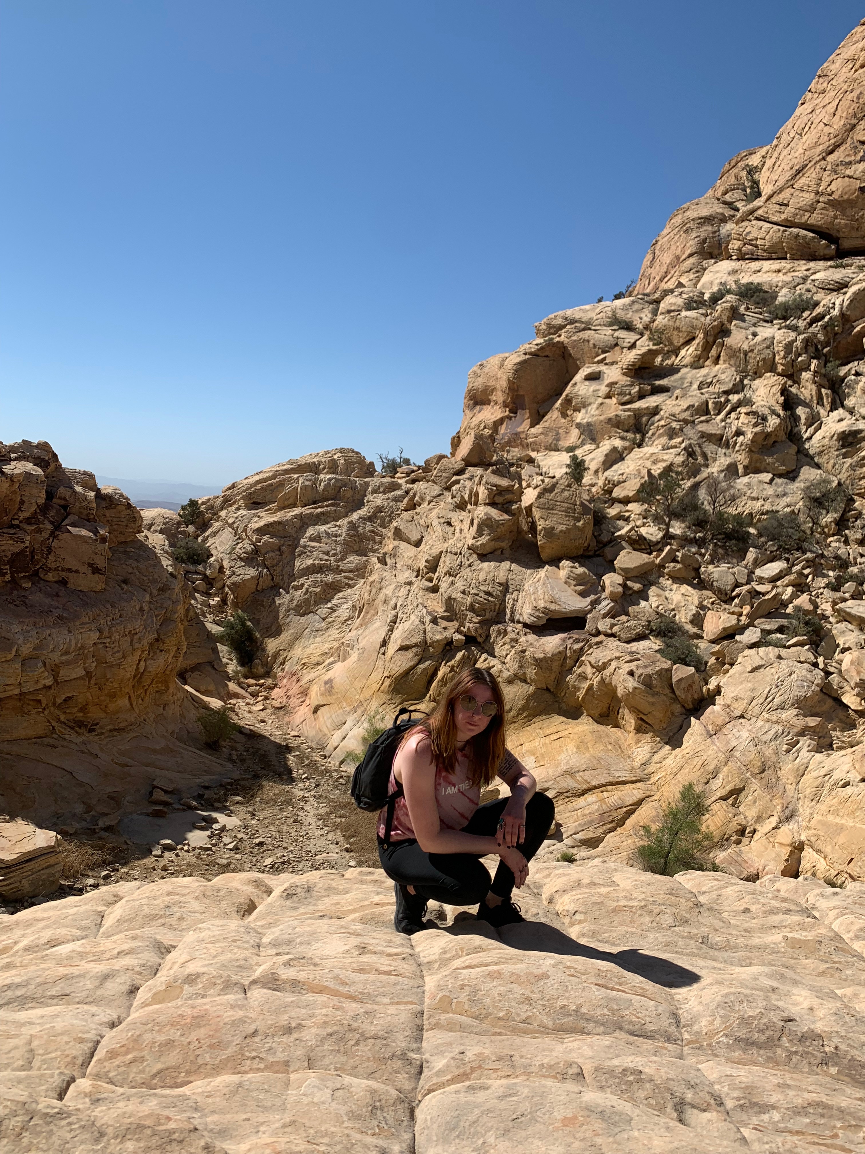 A woman crouching amng mountains in the desert
