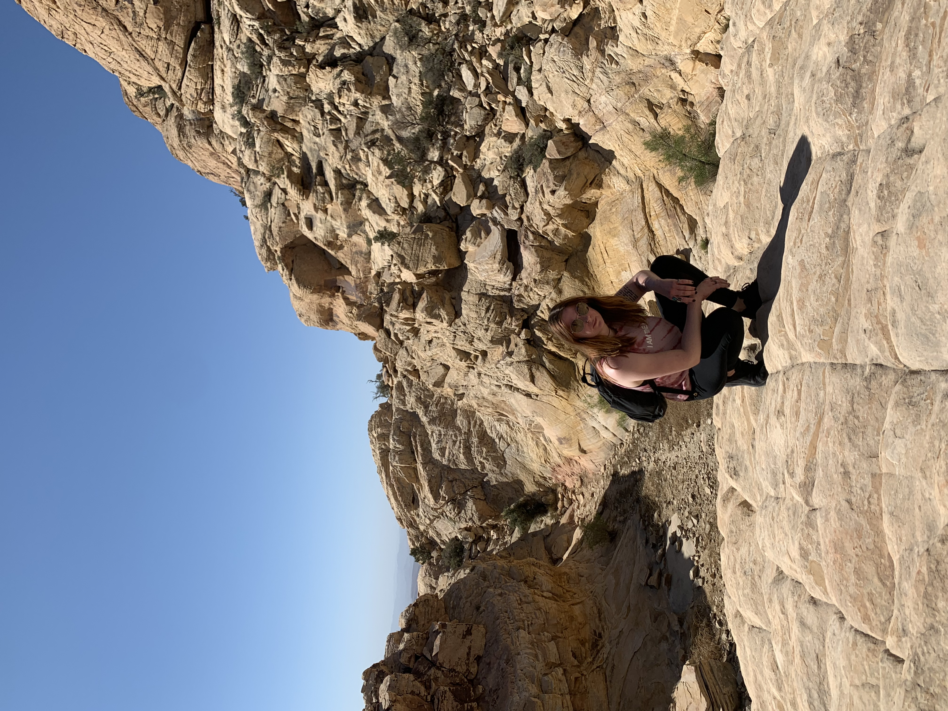 A woman crouching amng mountains in the desert